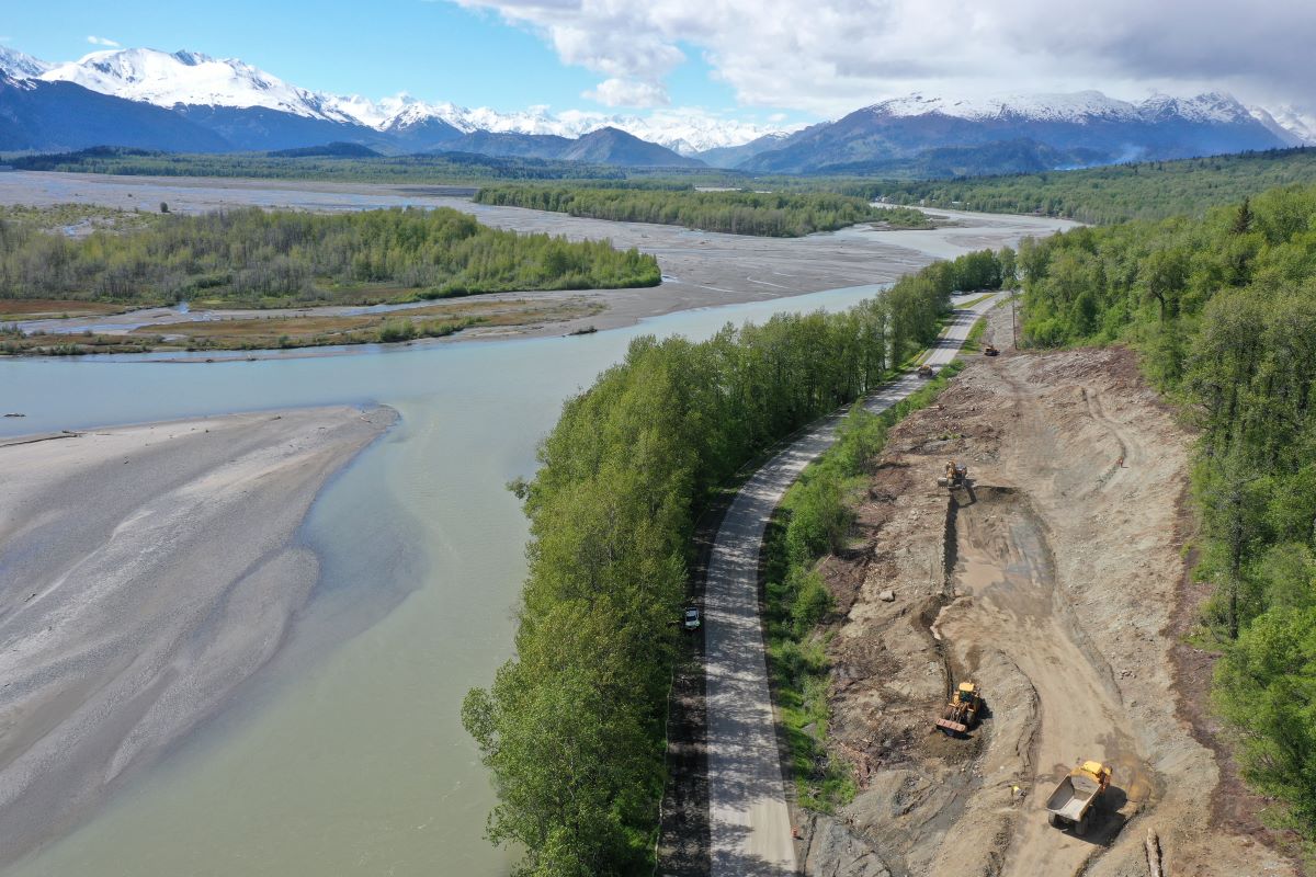 Lac avec une route, les montagnes derrières et un chantier en cours Route en Alaska
