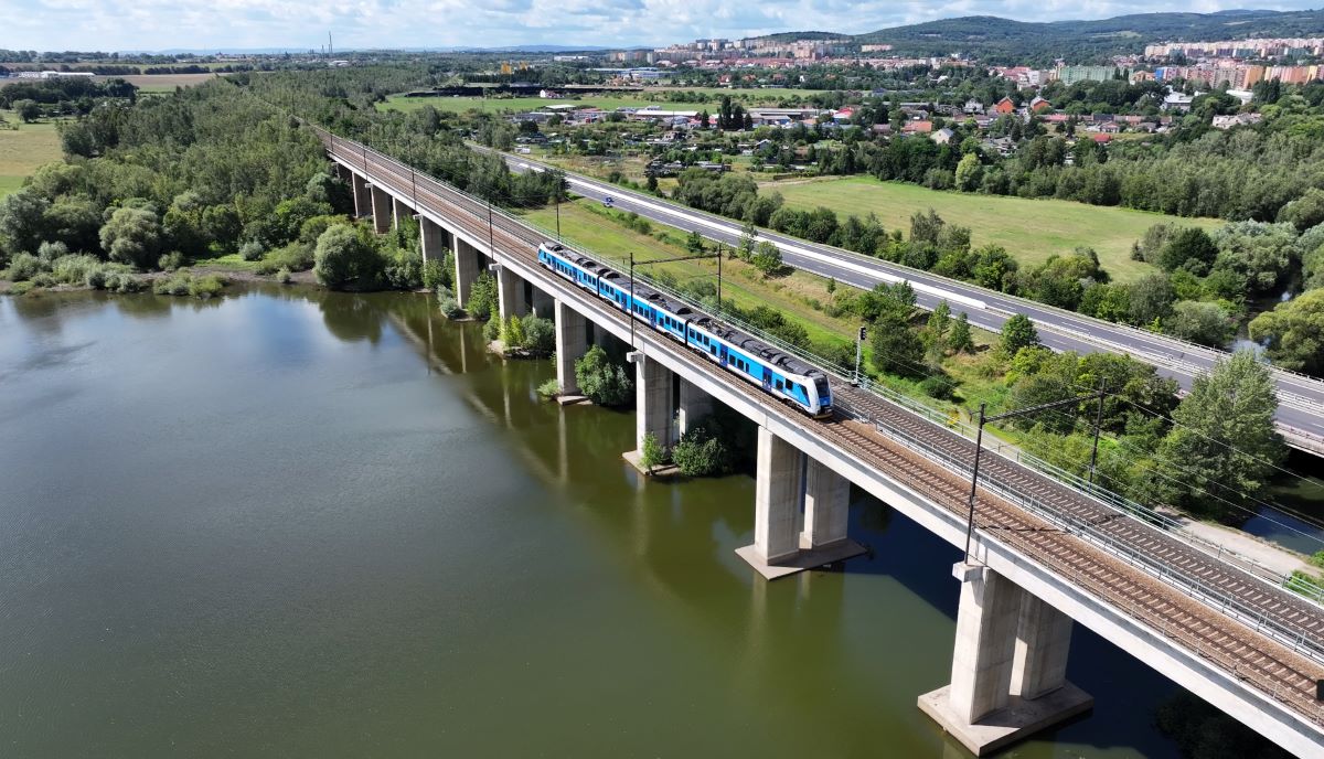 Pont ferroviaire traversant une rivière, train moderne, paysage verdoyant