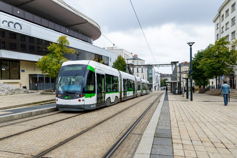 White and green tram that parks at a station