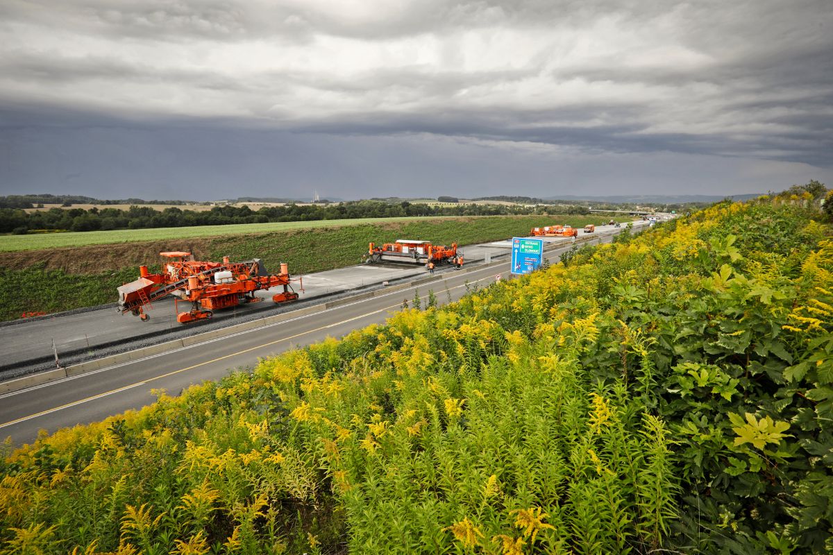 Travaux sur route de campagne sous ciel nuageux.