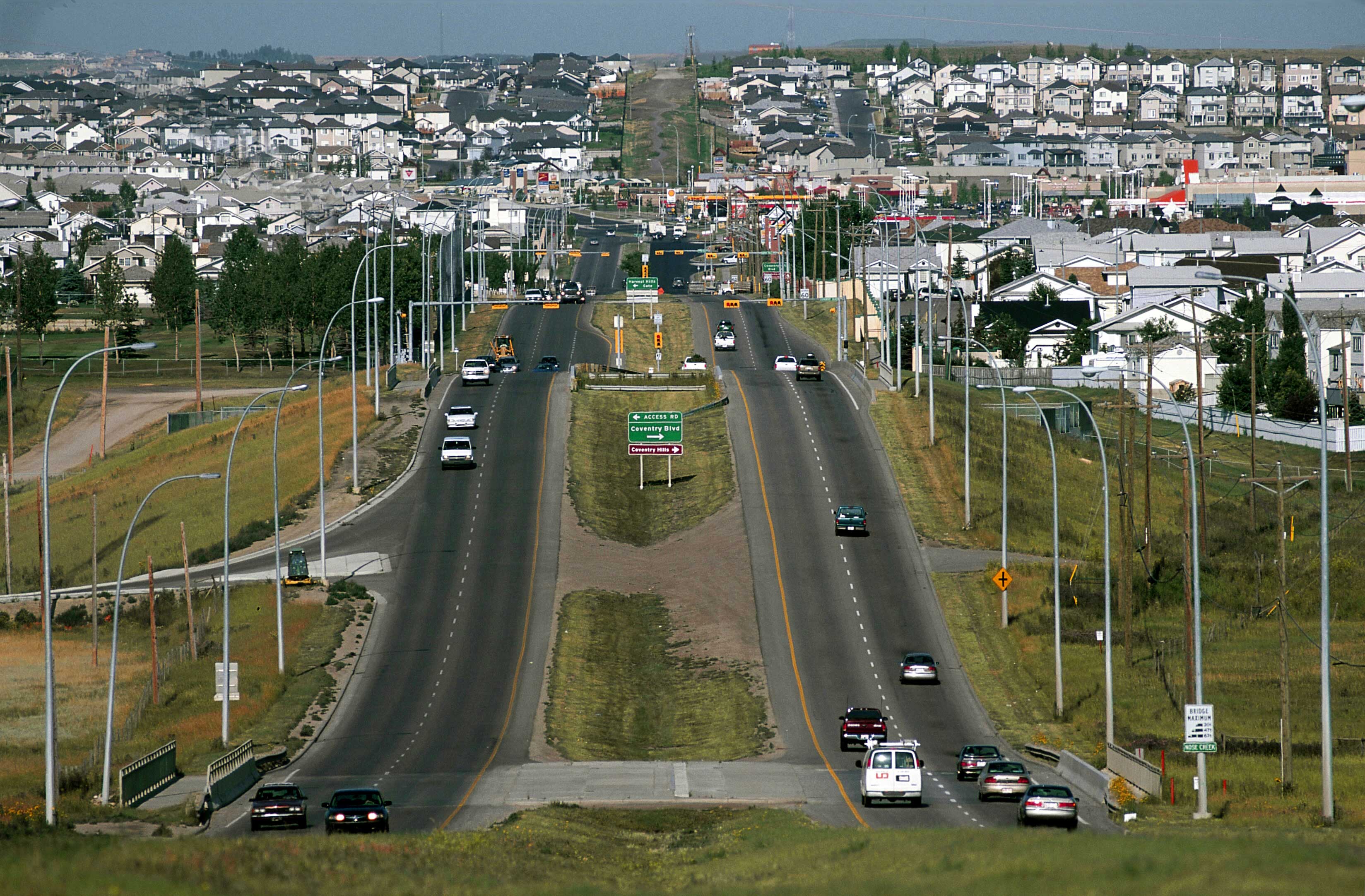 Busy urban road, moving cars, dense residential area in the background.
