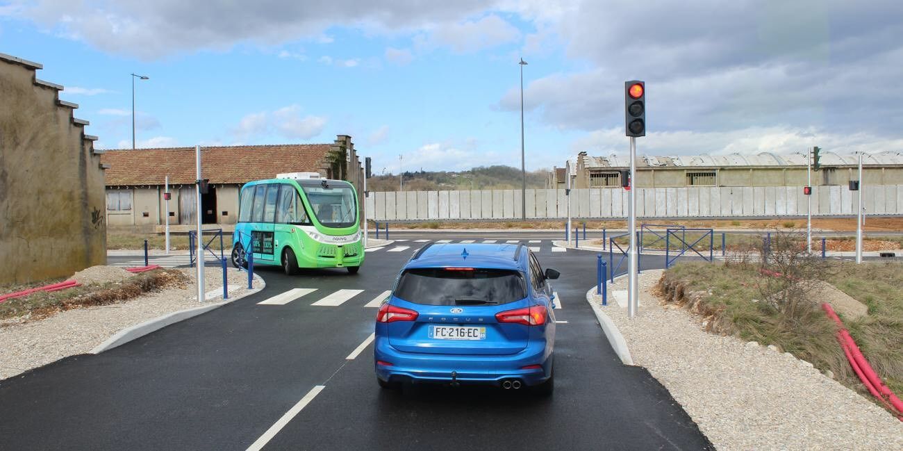 Blue car at a red light with a minibus