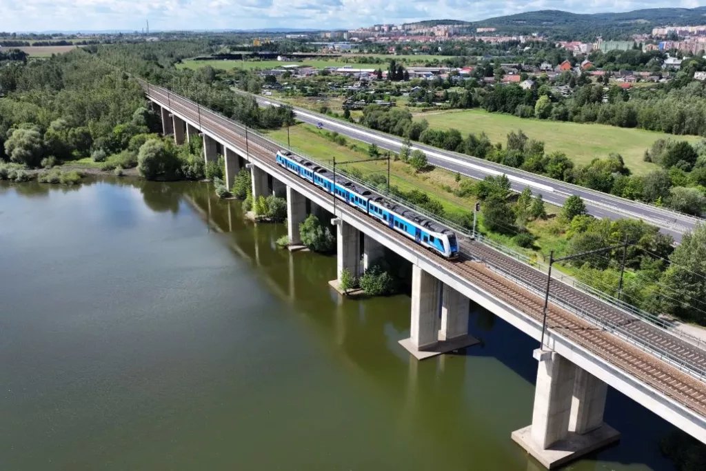 Pont ferroviaire traversant une rivière, train moderne, paysage verdoyant