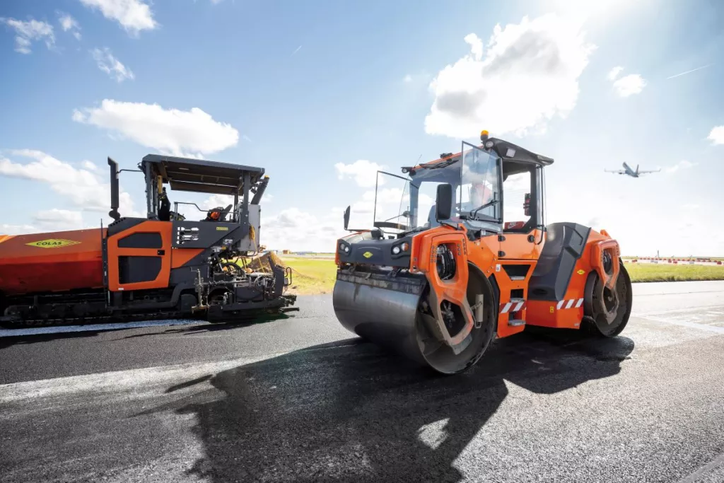 Road works with a compactor and a finisher on an airport runway