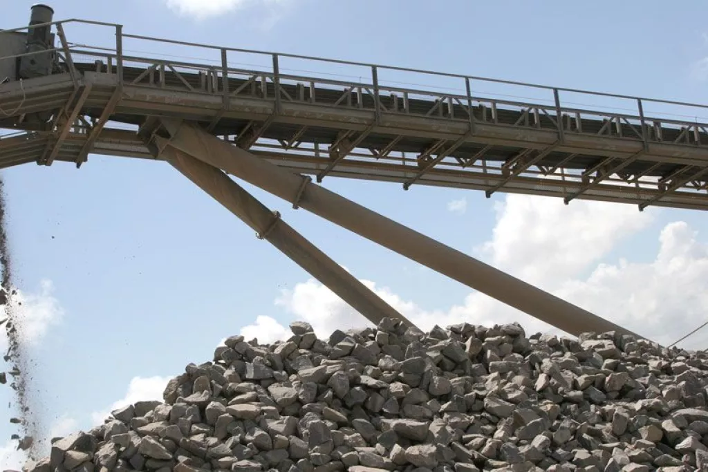 Une bande transporteuse de gravier déverse des pierres sur un tas