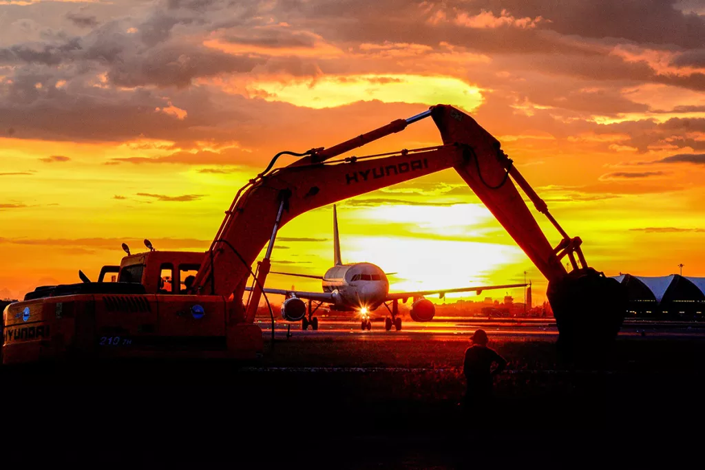 Sunset on an airport runway with planes and vehicles