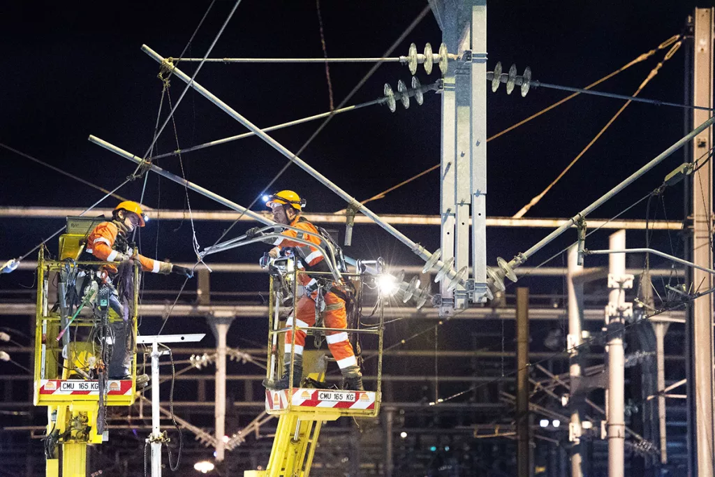 Collaborateurs en hauteur équipés de protection, effectuent des travaux sur une infrastructure électrique pendant la nuit