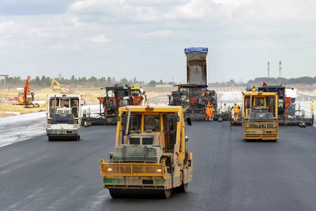 Chantier d'une piste d'aéroport où de nouvelles chaussées sont posées avec des engins