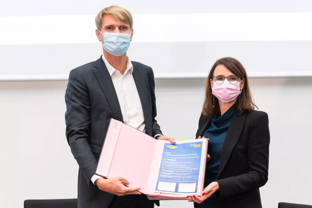 Deux personnes avec des masques posant avec un document signé