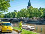 Agent d’entretien au bord de la rivière de Turku, avec véhicule d’intervention et pont en arrière-plan.