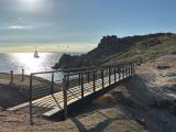 Passerelle côtière à Hoëdic avec vue sur l'océan et un voilier.