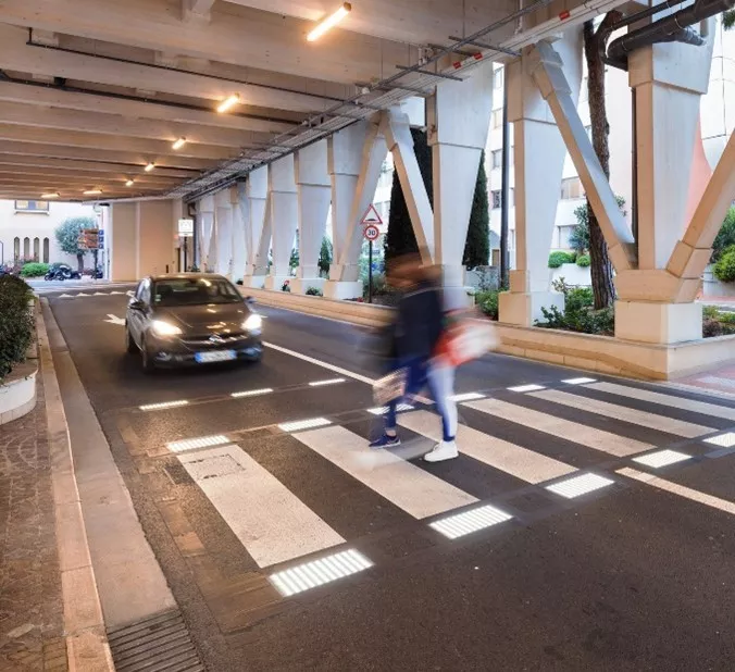 Person walking on a lit pedestrian crossing and a car waiting