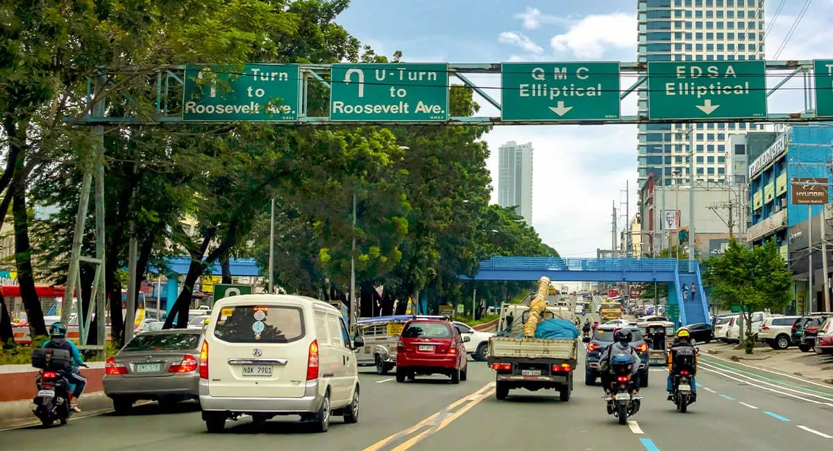 Circulation urbaine dense, panneaux routiers, bâtiments modernes en arrière-plan.