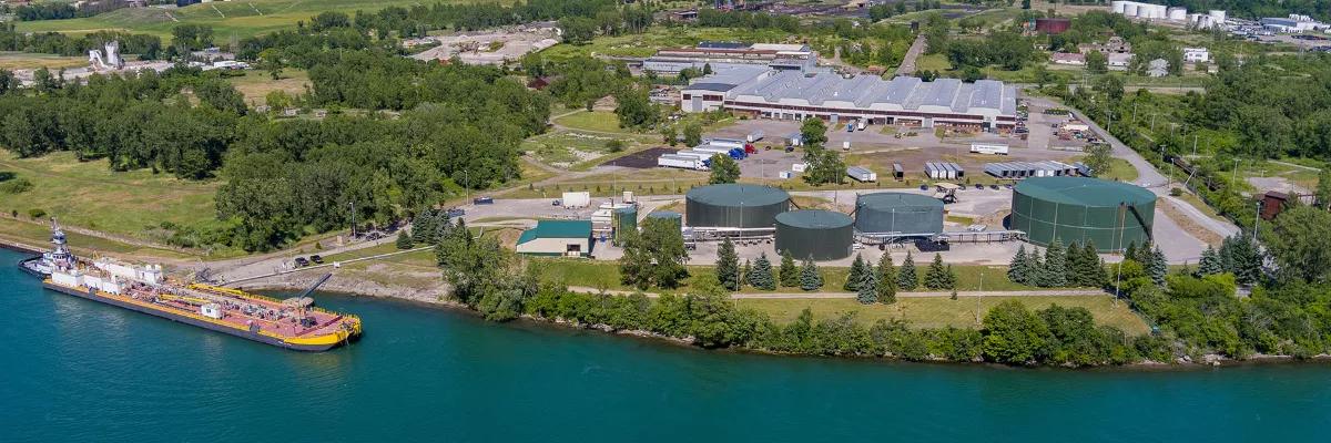 Industrial waterfront facility with storage tanks and docked ship.