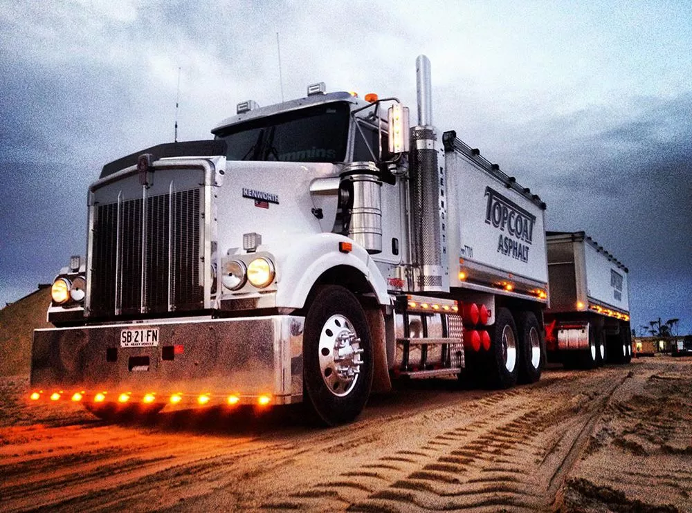 White truck transporting on a sandy terrain at dusk.