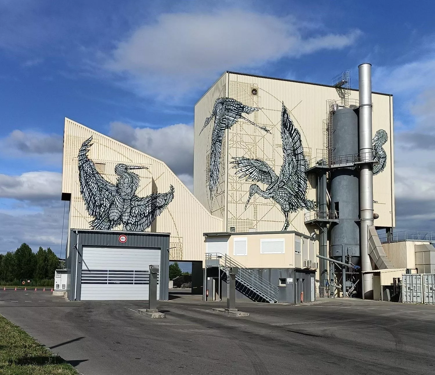 Industrial building, with large-scale murals depicting birds painted on its exterior walls
