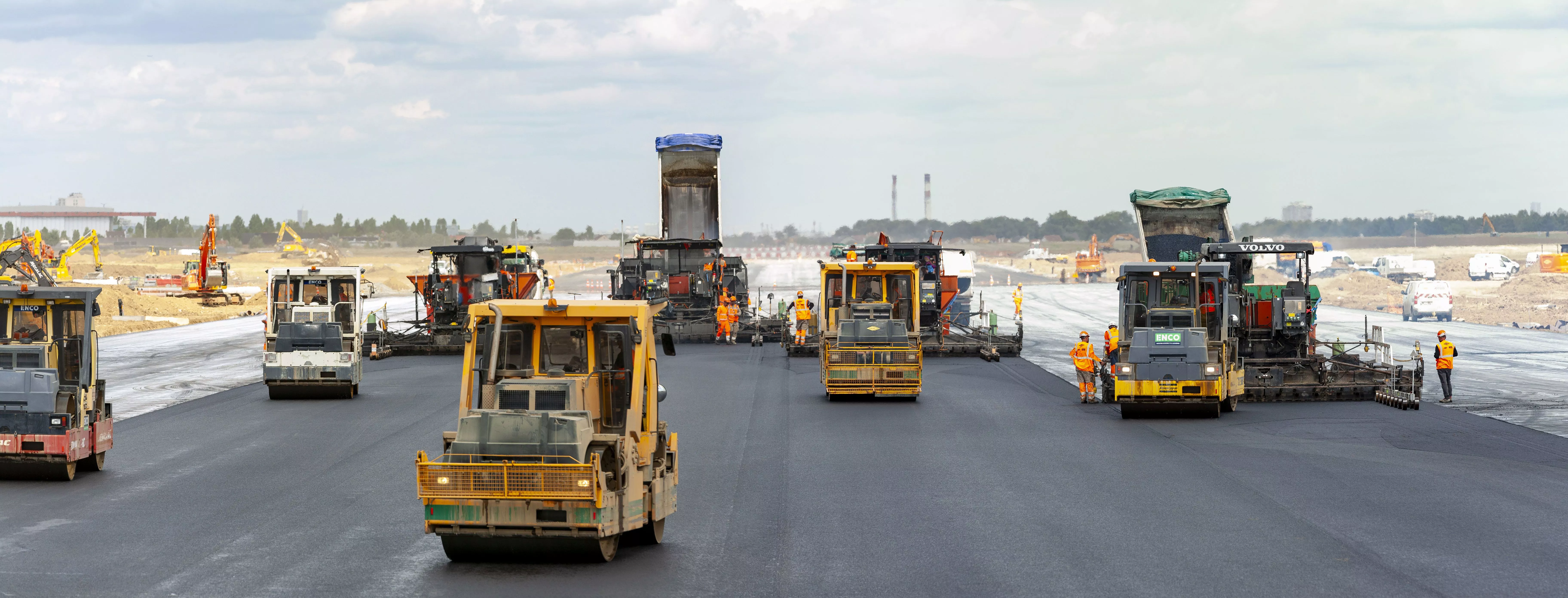 Chantier d'une piste d'aéroport où de nouvelles chaussées sont posées avec des engins