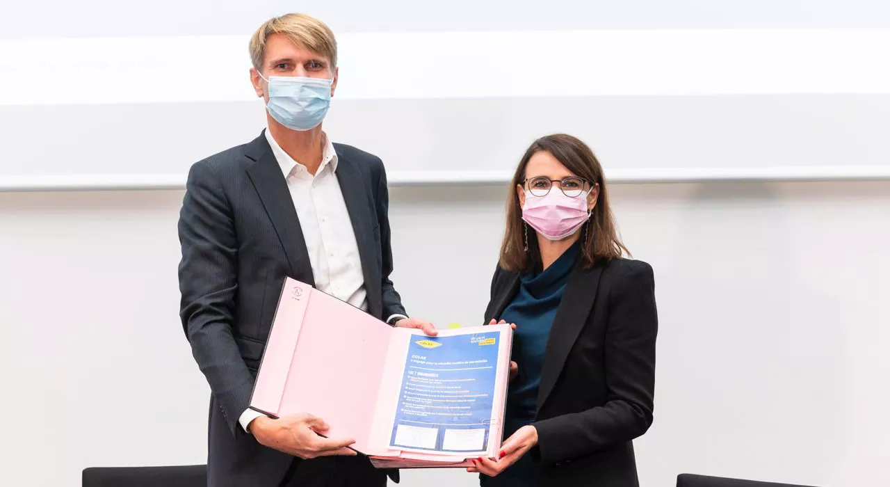Two people with masks posing with a signed document
