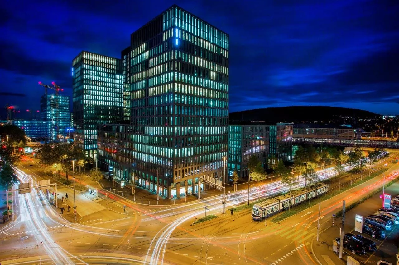 Modern night city with illuminated buildings, bright streaks of cars, dynamic atmosphere